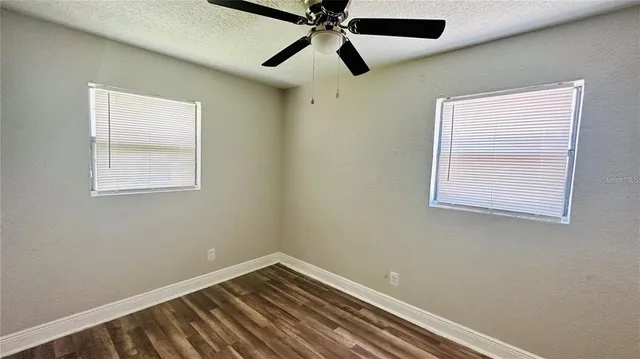 an empty room with a window and a fan