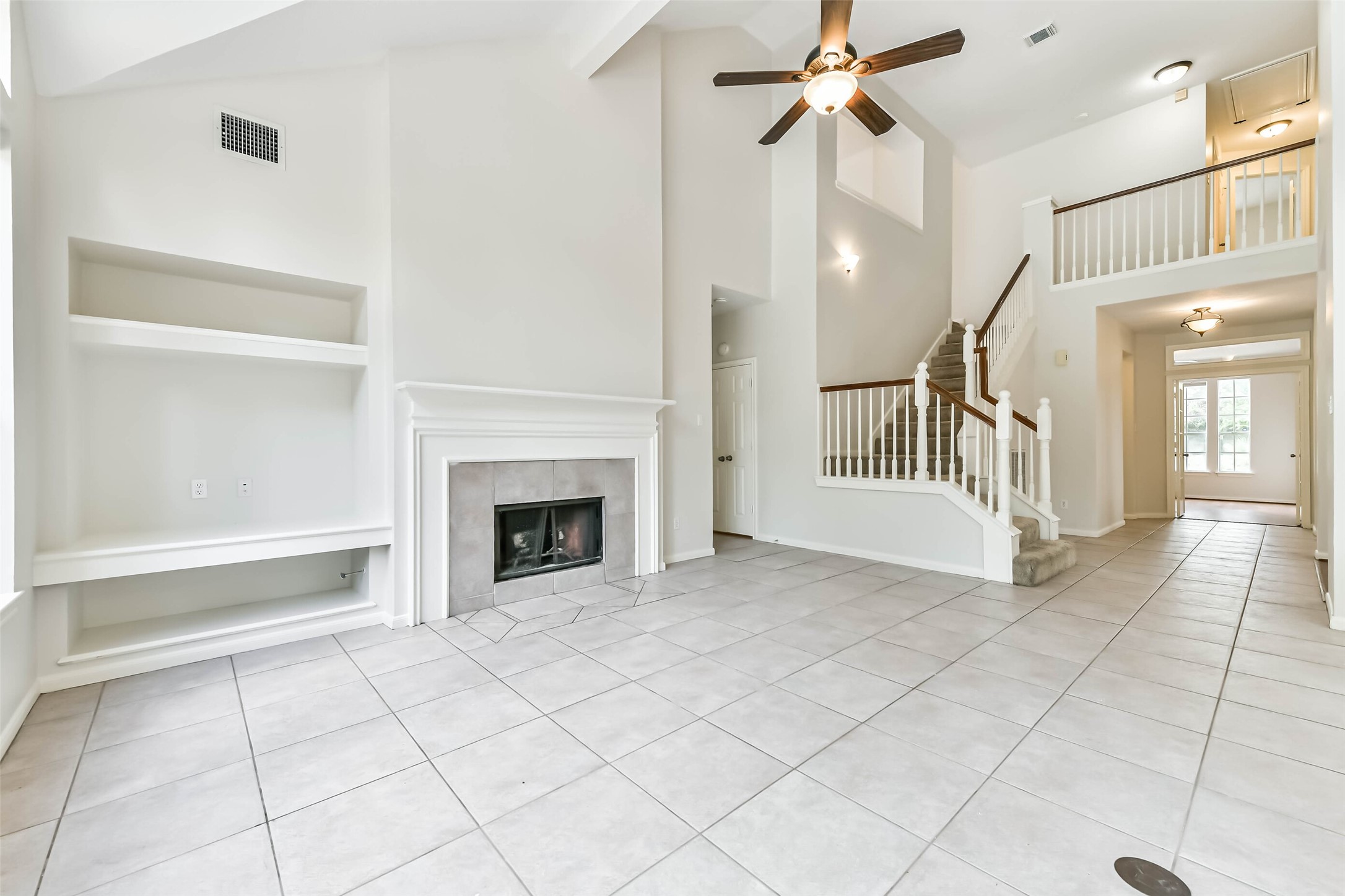 6338 Maple Spring Place Humble, TX 77346 - Photo 12 of 50 Picture your favorite seating gathered around the fireplace, with built-in shelving ready for books and personal treasures. The vaulted ceiling and open staircase give the room a spacious feel, while neutral finishes let your style take the lead.