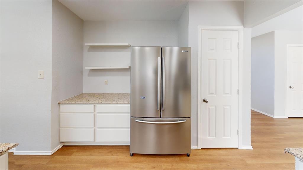 7913 Rice Drive Rowlett, TX 75088 - Photo 6 of 25 Stainless steel French door refrigerator with an adjacent built-in white cabinet with six drawers, speckled countertop, and two floating shelves