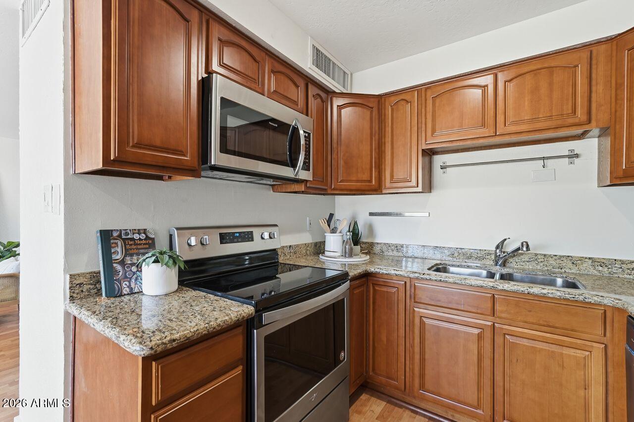 1012 East Osborn Road, Unit E Phoenix, AZ 85014 - Photo 11 of 22 a kitchen with stainless steel appliances granite countertop a sink stove and microwave