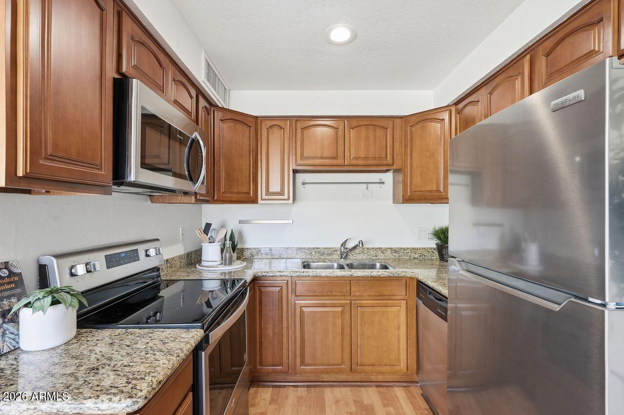 1012 East Osborn Road, Unit E Phoenix, AZ 85014 - Photo 12 of 22 a kitchen with stainless steel appliances granite countertop a sink stove and refrigerator