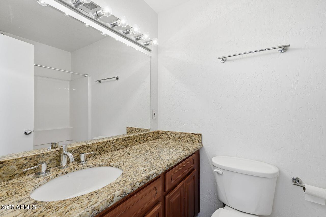 1012 East Osborn Road, Unit E Phoenix, AZ 85014 - Photo 18 of 22 a bathroom with a granite countertop sink a toilet and a mirror