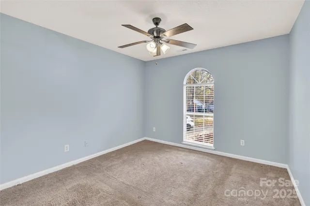 an empty room with windows and ceiling fan