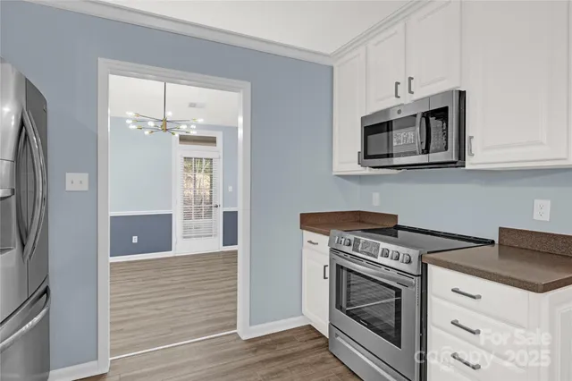 a kitchen with stainless steel appliances granite countertop white cabinets a refrigerator and a stove top oven