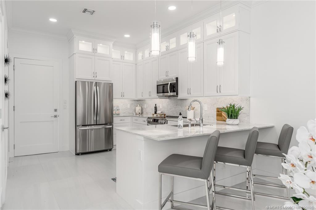4674 Southeast Manatee Terrace Stuart, FL 34997 - Photo 36 of 55 a kitchen with kitchen island a appliances a sink and a refrigerator