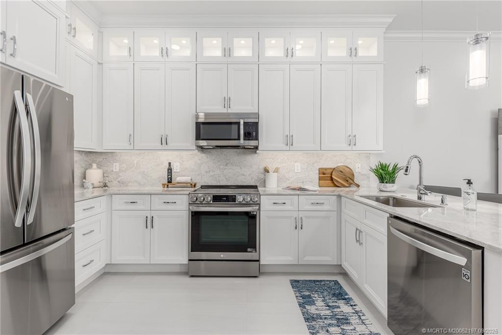 4674 Southeast Manatee Terrace Stuart, FL 34997 - Photo 37 of 55 a kitchen with stainless steel appliances granite countertop a stove a sink and a refrigerator