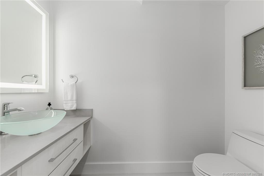 4674 Southeast Manatee Terrace Stuart, FL 34997 - Photo 39 of 55 a bathroom with a granite countertop sink vanity mirror and toilet