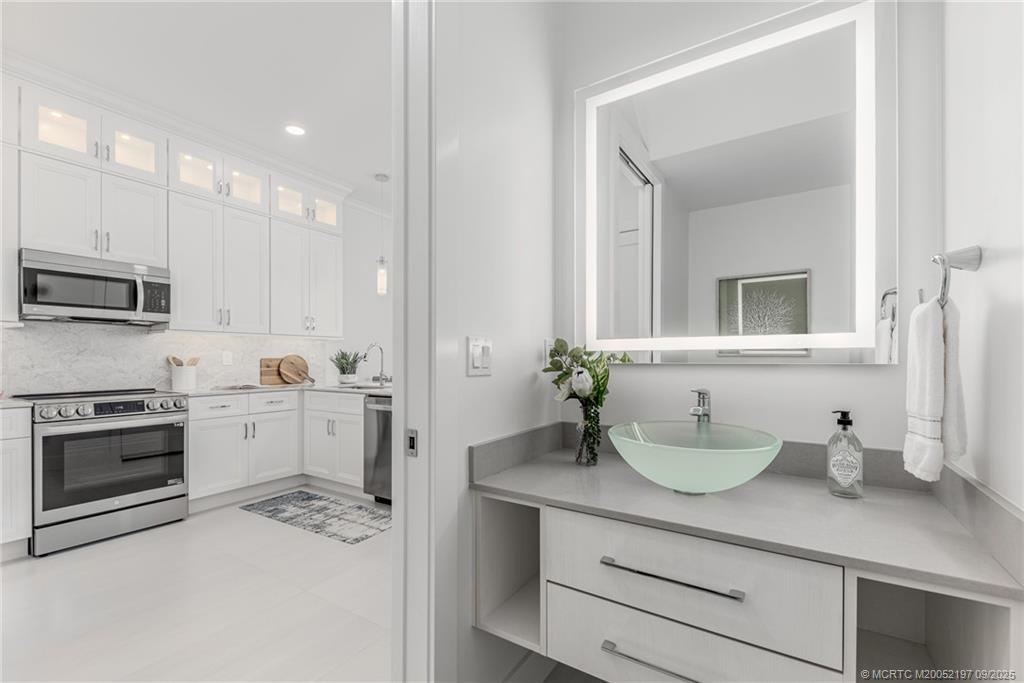 4674 Southeast Manatee Terrace Stuart, FL 34997 - Photo 40 of 55 a spacious bathroom with a granite countertop sink and a mirror