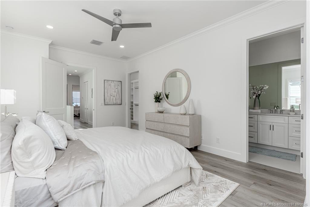 4674 Southeast Manatee Terrace Stuart, FL 34997 - Photo 48 of 55 a bedroom with a bed a chandelier and mirror