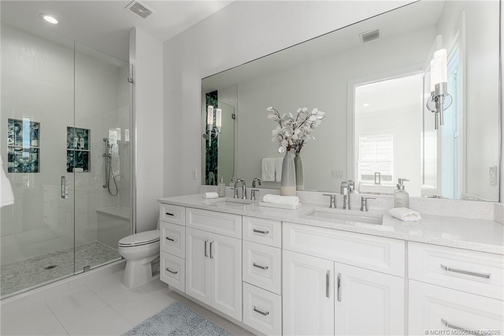 4674 Southeast Manatee Terrace Stuart, FL 34997 - Photo 49 of 55 a bathroom with a double vanity sink toilet and shower