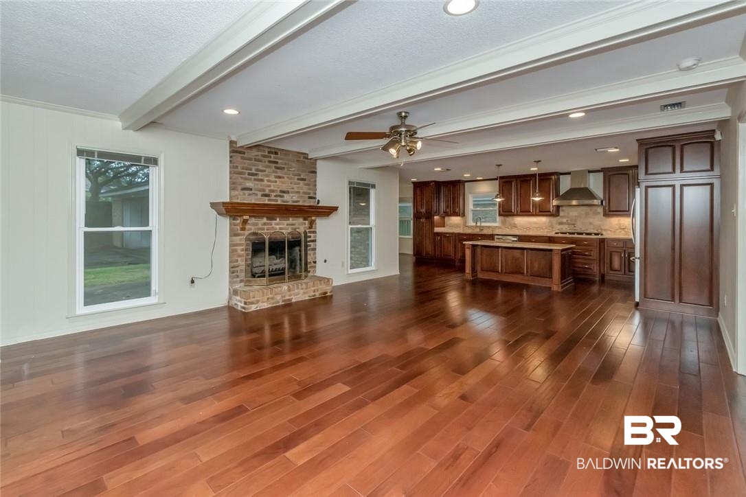 6109 Timberly Road North Mobile, AL 36609 - Photo 7 of 26 Unfurnished living room featuring a textured ceiling, dark hardwood / wood-style floors, beam ceiling, a fireplace, and ceiling fan