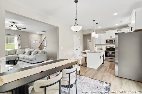 a kitchen with stainless steel appliances kitchen island granite countertop a refrigerator a stove and white cabinets with wooden floor
