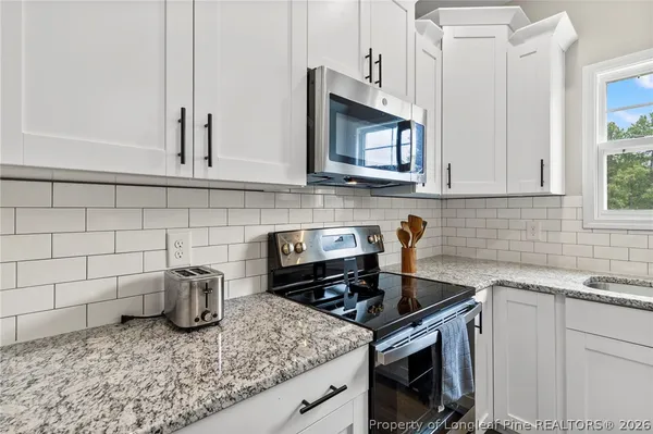 a kitchen with granite countertop a sink stainless steel appliances and cabinets