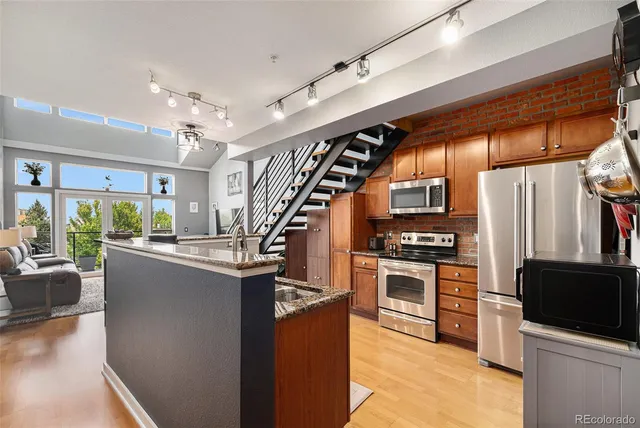 a kitchen with stainless steel appliances granite countertop a refrigerator a stove and a microwave