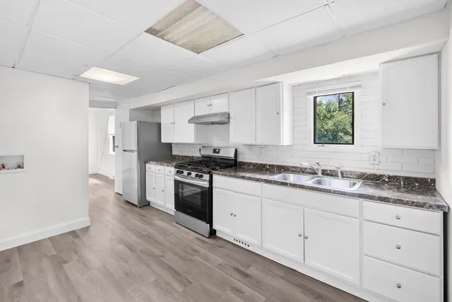 a kitchen with granite countertop a sink cabinets stainless steel appliances and a window