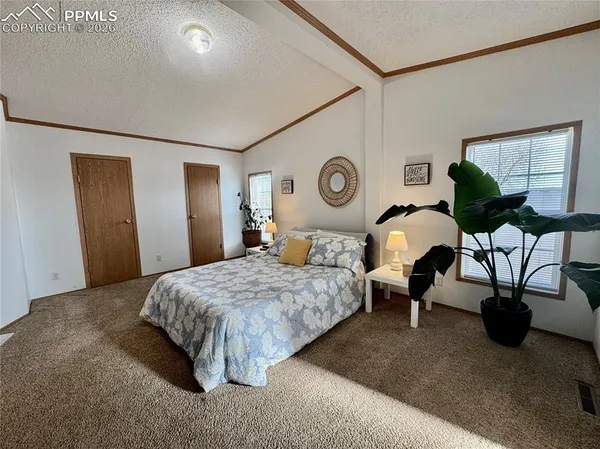a bedroom with a bed a wall painting and a potted plant