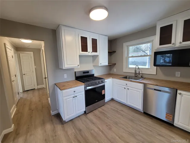 a large kitchen with stainless steel appliances granite countertop a stove a sink dishwasher and a microwave oven with wooden floor