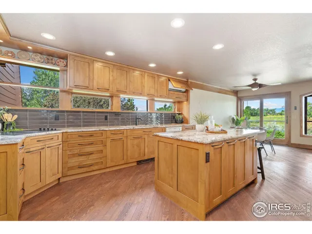a kitchen with stainless steel appliances kitchen island granite countertop a table chairs sink and cabinets
