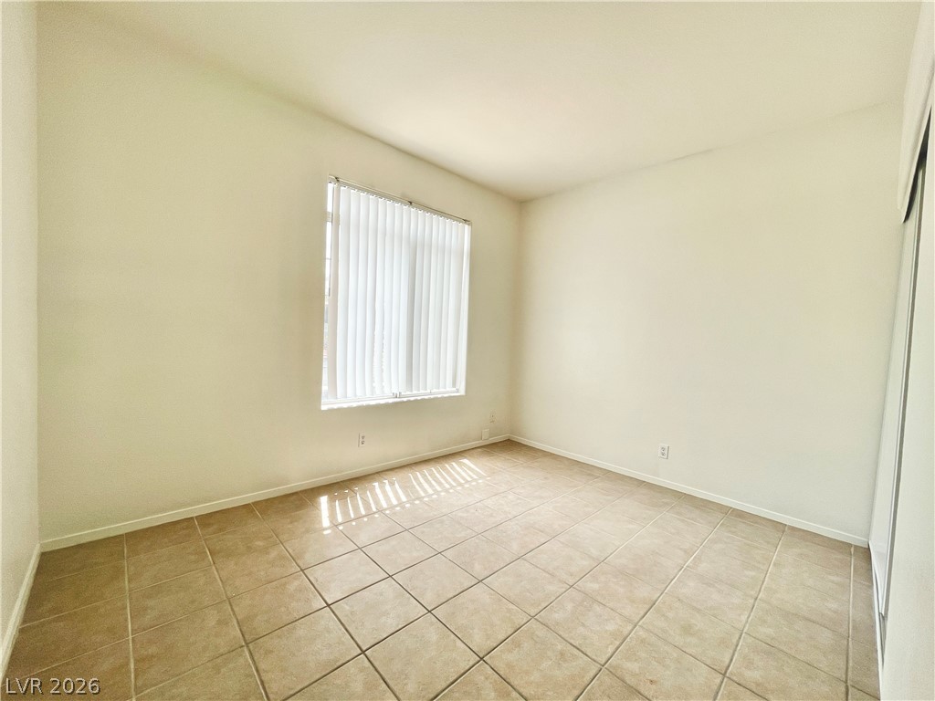 2201 Ramsgate Drive, Unit 915 Henderson, NV 89074 - Photo 22 of 36 Natural light filters through vertical blinds into this neatly tiled bedroom space.
