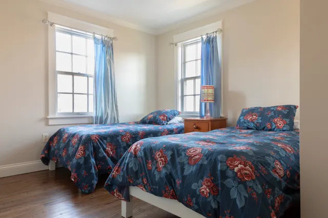 a bedroom with two beds and wooden floor