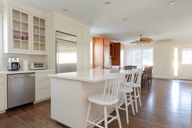 a kitchen with stainless steel appliances granite countertop a dining table chairs and granite counter tops