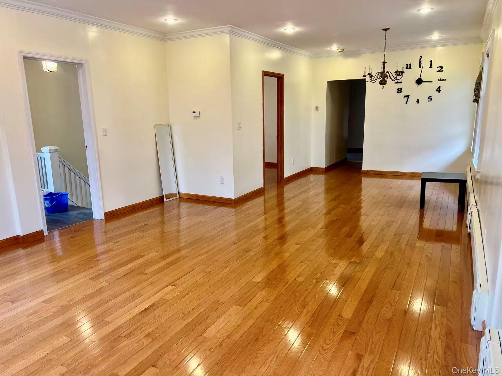 149-15 15th Road Queens, NY 11357 - Photo 3 of 20 a view of an empty room with wooden floor and a kitchen