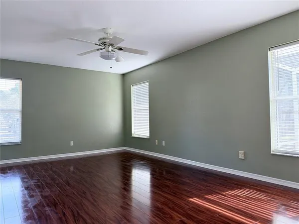 a view of an empty room with window and wooden floor