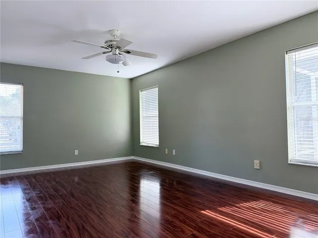a view of an empty room with window and wooden floor