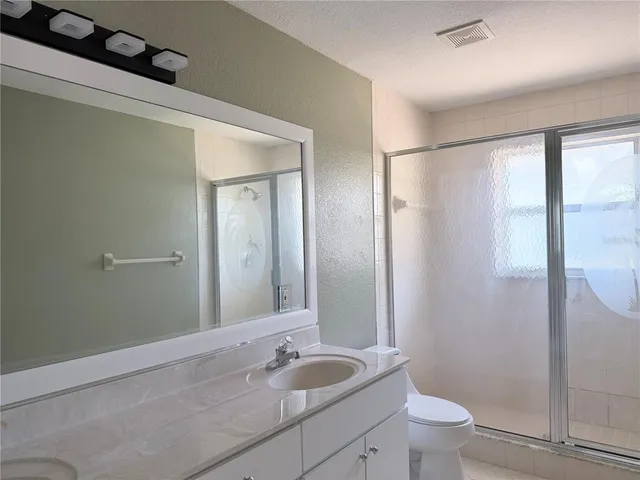 a bathroom with a granite countertop sink a toilet and shower