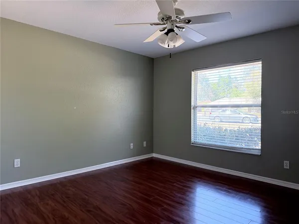 a view of an empty room with wooden floor and a window
