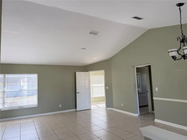 a view of an empty room with window and cabinet area