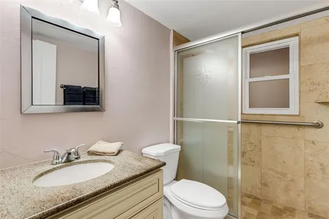 a bathroom with a granite countertop sink toilet a mirror and shower