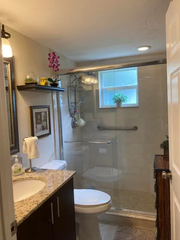 a bathroom with a granite countertop sink mirror vanity and toilet