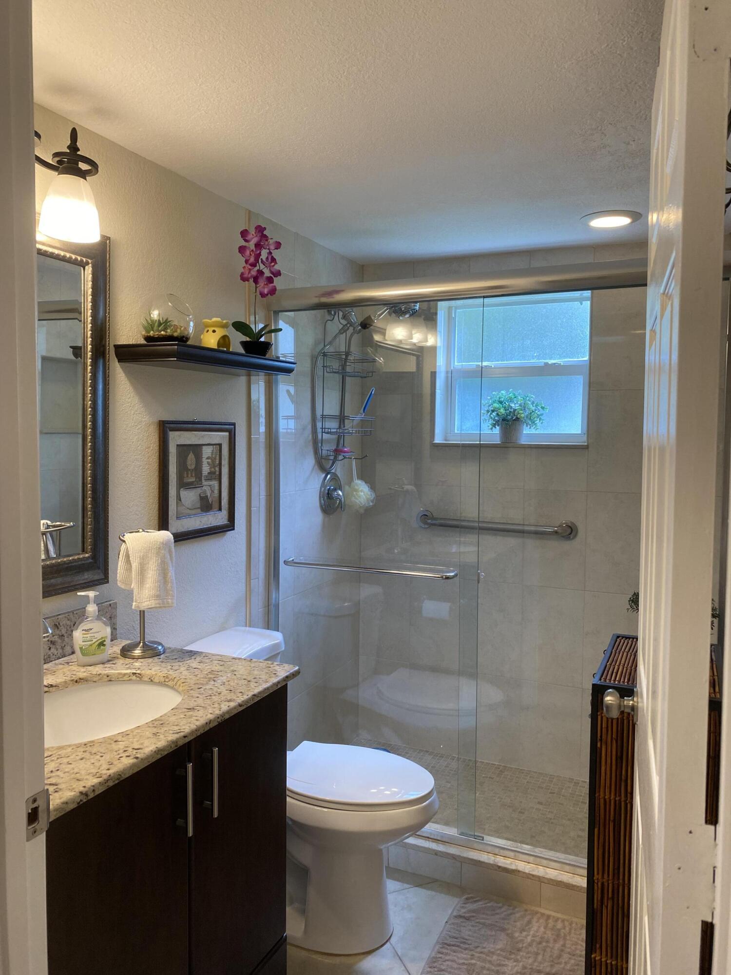 148 Normandy Lane Delray Beach, FL 33484 - Photo 18 of 29 a bathroom with a granite countertop sink a toilet and shower