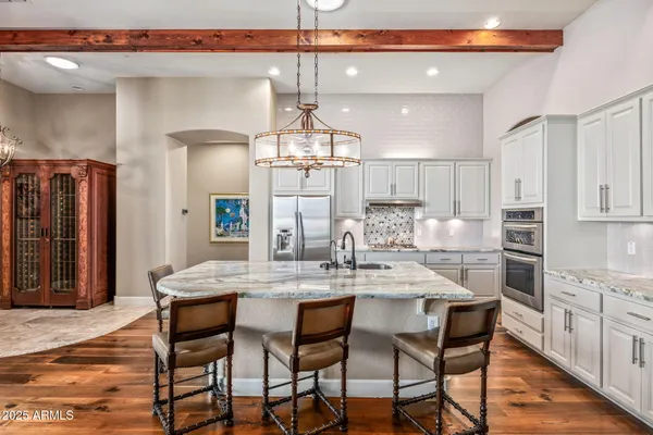 a kitchen with stainless steel appliances kitchen island granite countertop a dining table chairs and white cabinets