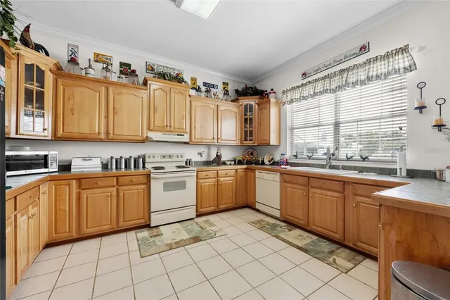 a kitchen with a sink a stove top oven and white cabinets