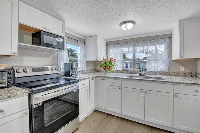 a kitchen with granite countertop a sink cabinets stainless steel appliances and a window