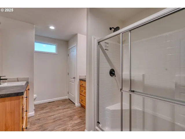 a view of an empty room with wooden floor and a bathroom