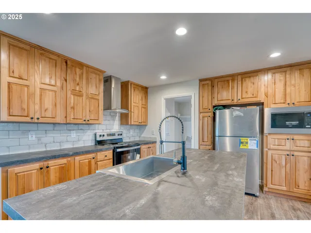 a kitchen with stainless steel appliances granite countertop a sink refrigerator stove and microwave