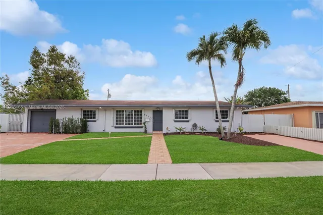 a front view of a house with a garden and trees