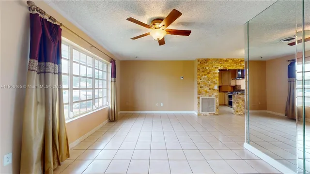 a view of an empty room with window and a kitchen view