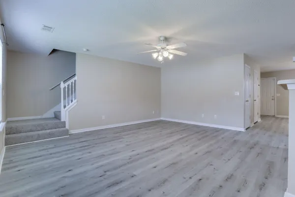 a view of empty room with wooden floor and ceiling fan