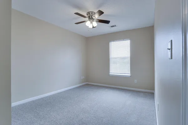 an empty room with a window and a ceiling fan