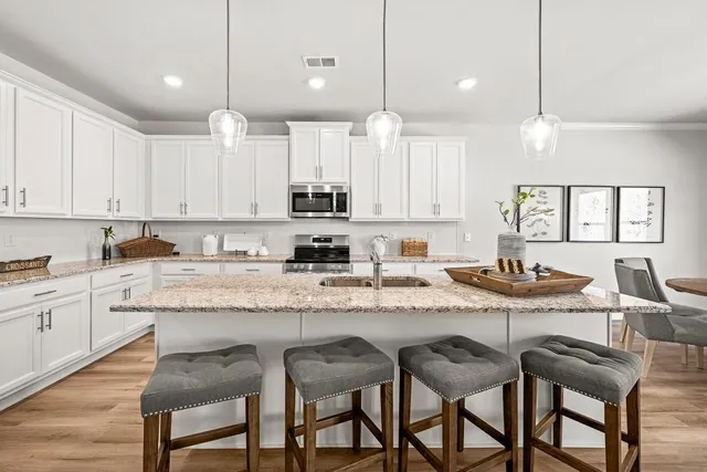 a kitchen with stainless steel appliances granite countertop a stove a sink a dining table and chairs with wooden floor