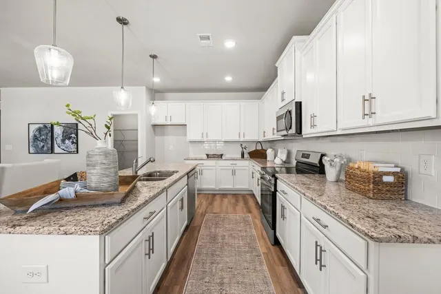 a kitchen with granite countertop a sink a counter space appliances and cabinets