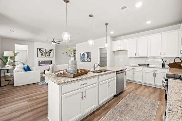 a open kitchen with granite countertop a sink window and white cabinets
