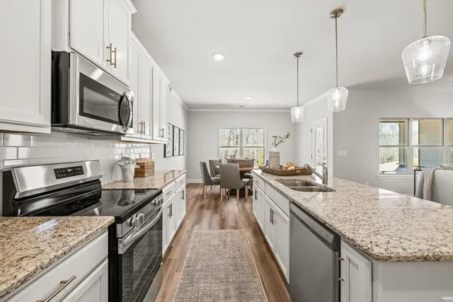 a kitchen with stainless steel appliances granite countertop a stove a sink and a microwave