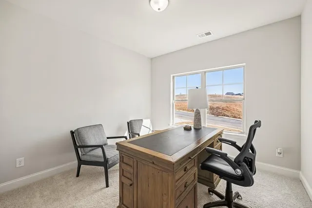 a view of a workspace with furniture and a window