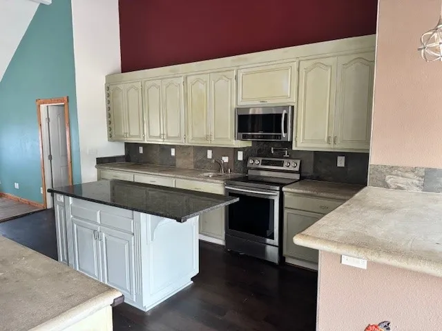 a kitchen with granite countertop a sink stove and microwave