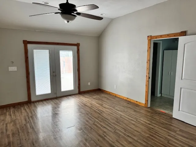 a view of an empty room with wooden floor and a ceiling fan